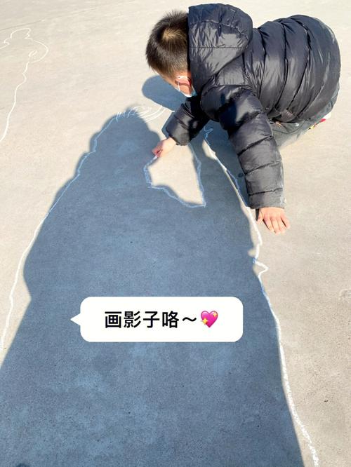 儿童用彩色粉笔在小区水泥地上画太阳影子轮廓的实景