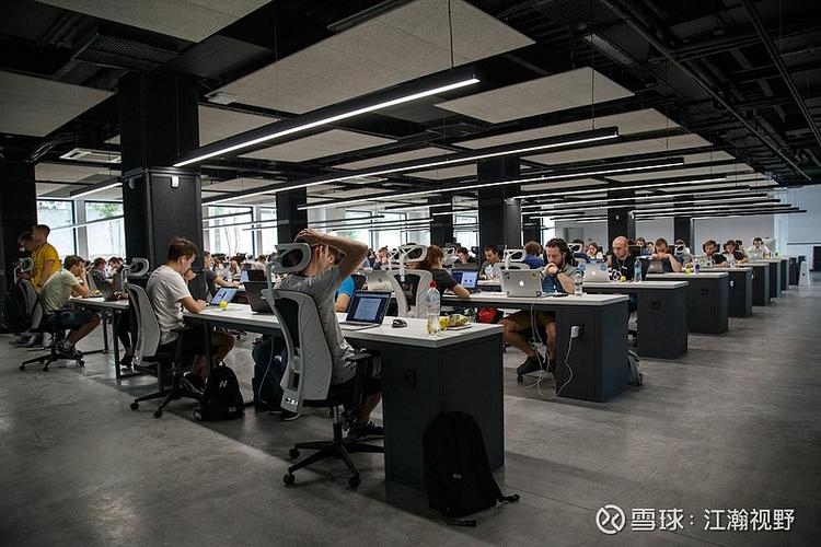 数字游民在里斯本共享办公空间使用电脑并与他人交流的场景