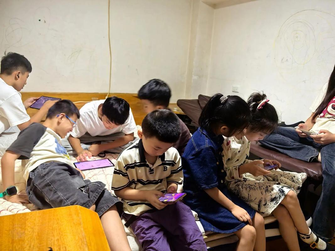 小学操场学生课间无精打采坐着玩手机场景