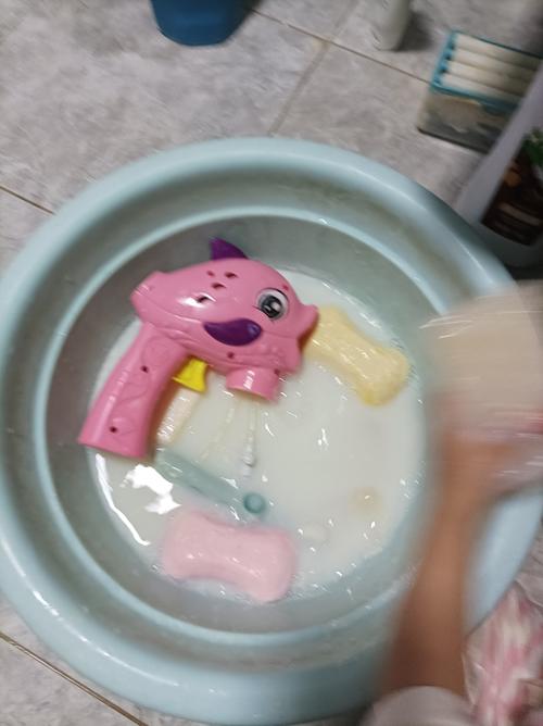 小学生在浴室洗澡盆边把塑料玩具放进水里观察沉浮