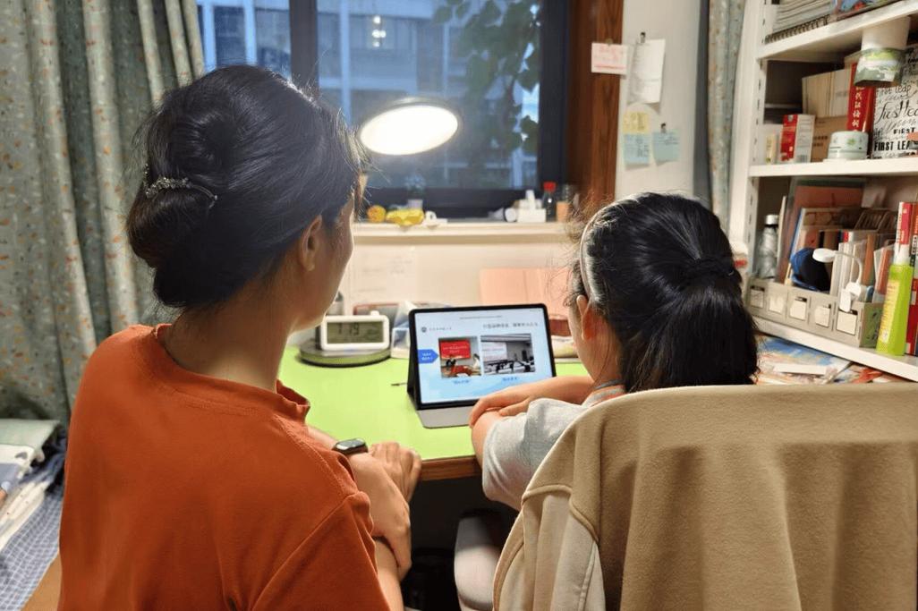家长使用平板电脑参加线上家长会的插图