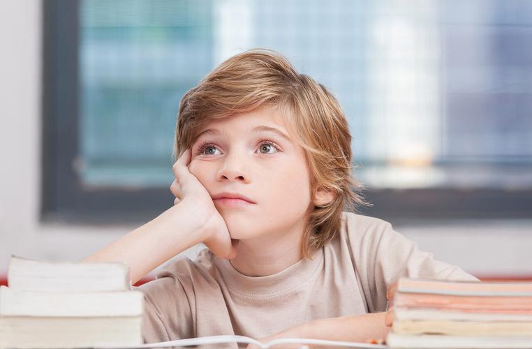书桌前托着腮发呆的小学三年级孩子