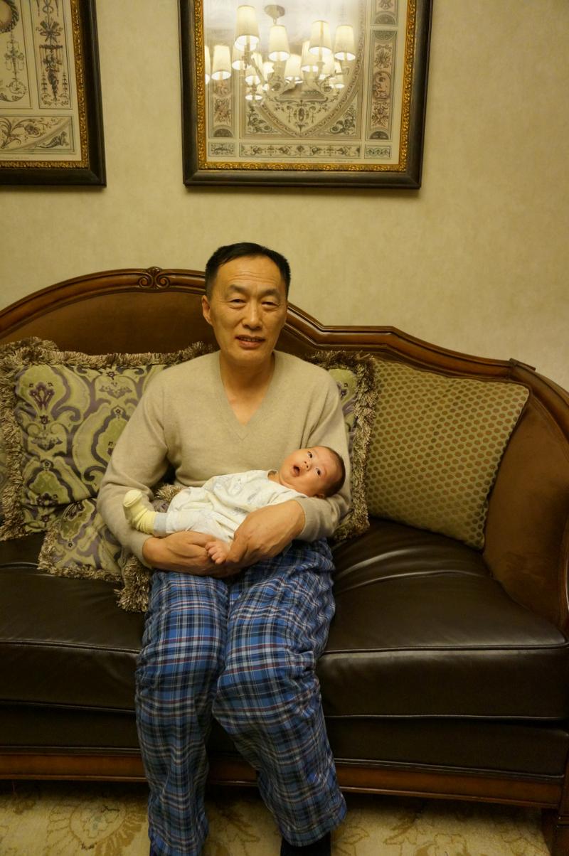 爷爷抱着幼儿在沙发讲睡前故事的客厅场景