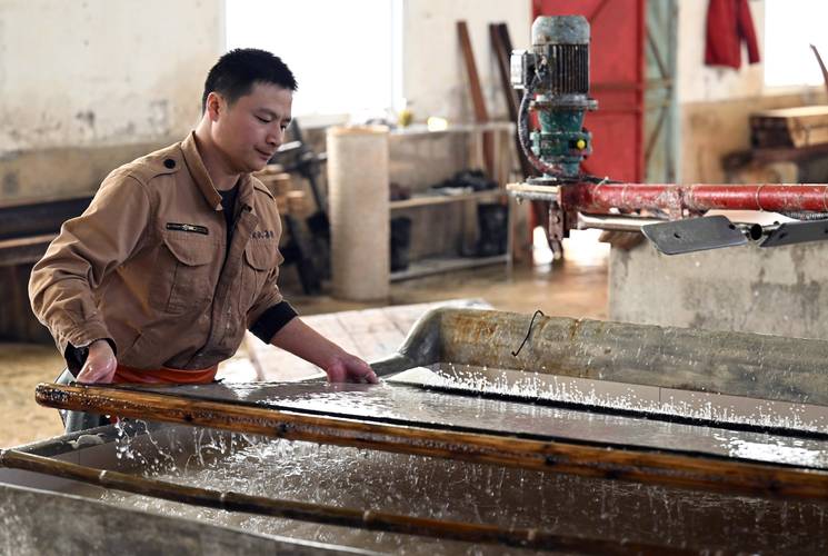 传统五金厂车间工人手持浸皱的纸质工单场景