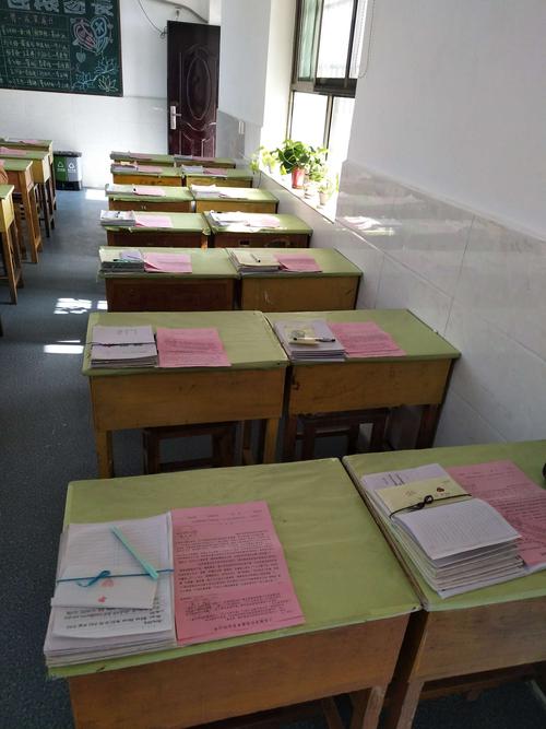 初中教室走廊放着摊开学生作文本的木质监考桌