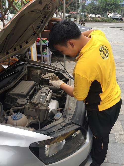 汽修厂技师蹲在车边摸汽车排气管外壁测温度