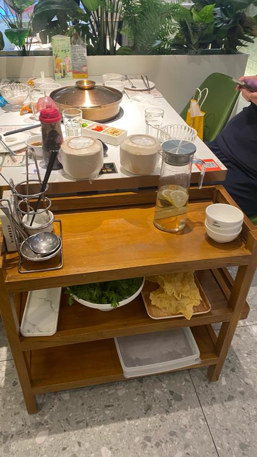 火锅店木质餐桌上放半凉的毛肚和亮屏的智能手机