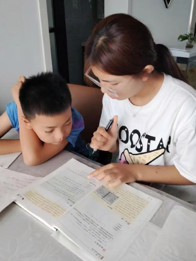 家长和孩子坐在书桌前一起分析考试成绩单场景