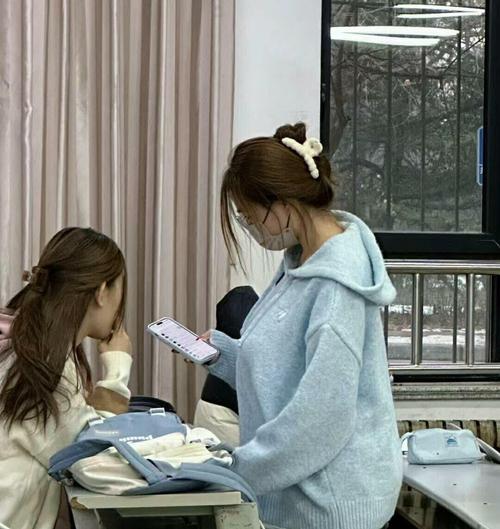 初中教室后排学生凑头偷看青春期健康课本
