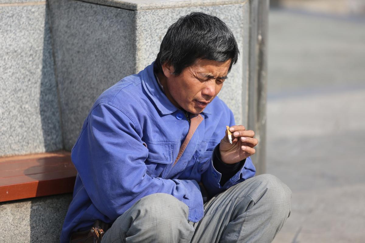 珠三角工业区门口抽烟休息的中年工人