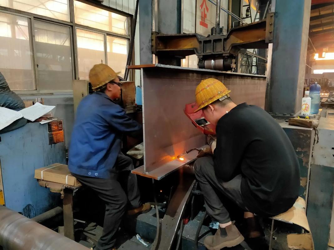 钢结构加工车间内，工人正在操作H型钢组立机进行组对