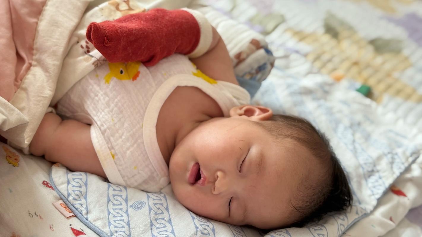 家长把婴儿袜子套在手指头上逗宝宝的实拍图