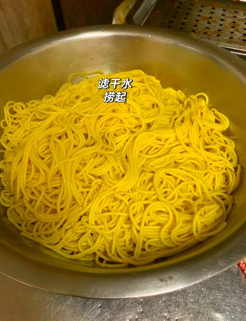 煮好的面条在漏勺中过凉水冲淋的操作图
