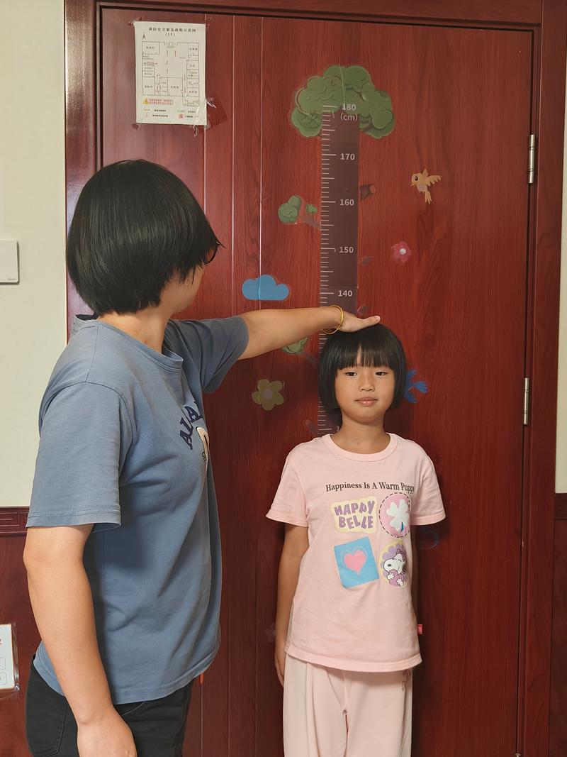 家长在家给学龄前儿童测体重场景图
