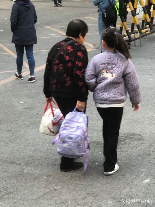 奶奶帮小学生背书包进校园场景