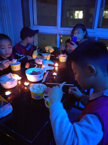 晚饭桌上孩子拿卷纸筒当话筒给家人讲故事的日常场景