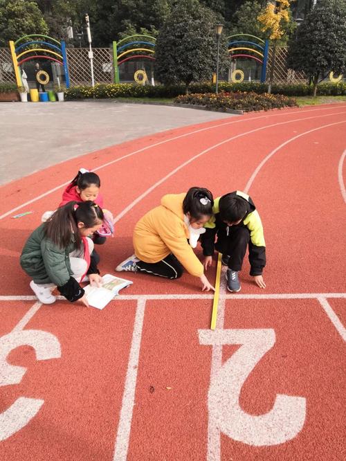 小学生拿着卷尺在校园草坪边测量点位距离的实践场景