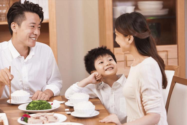 餐桌边妈妈和小学儿子一起看手机屏幕聊天