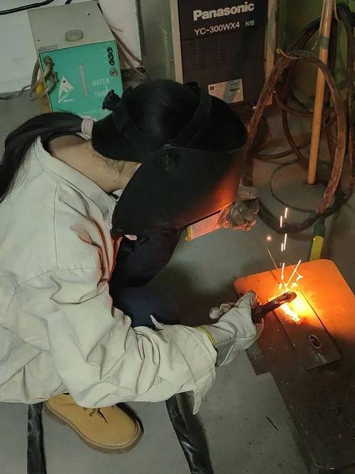 年轻女性焊工在车间练习焊接