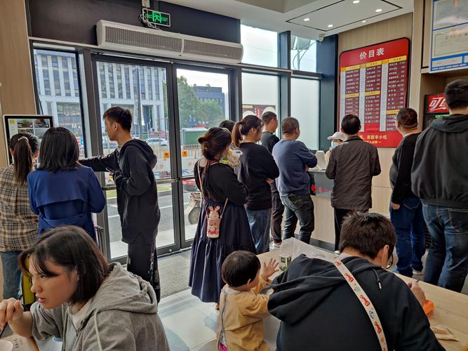 排队人群中有店员举着二维码牌示意顾客扫码领优惠