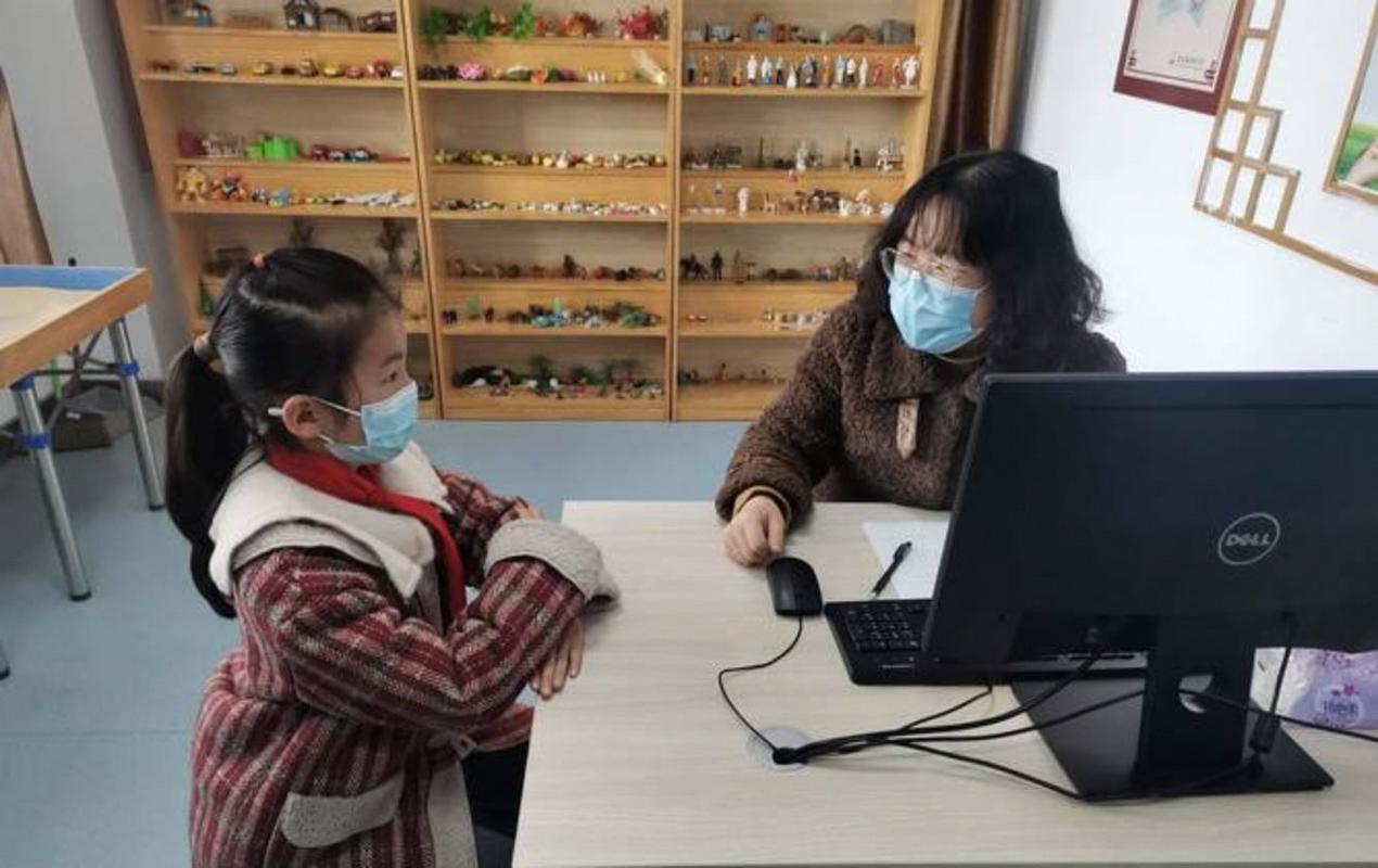 初中教师在办公桌前批评低头站立的男学生
