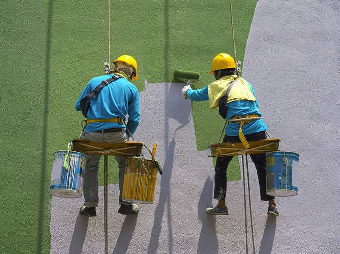 油漆工手持喷枪喷涂金属漆墙面