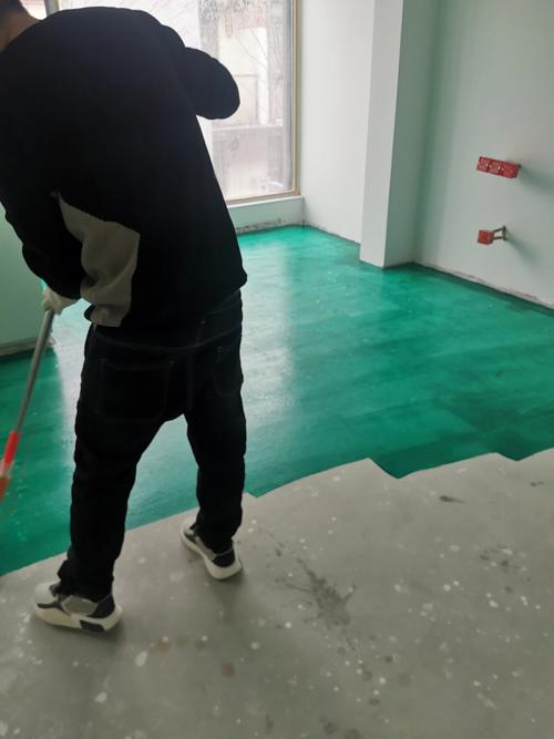 工人用滚筒涂刷地固施工过程特写