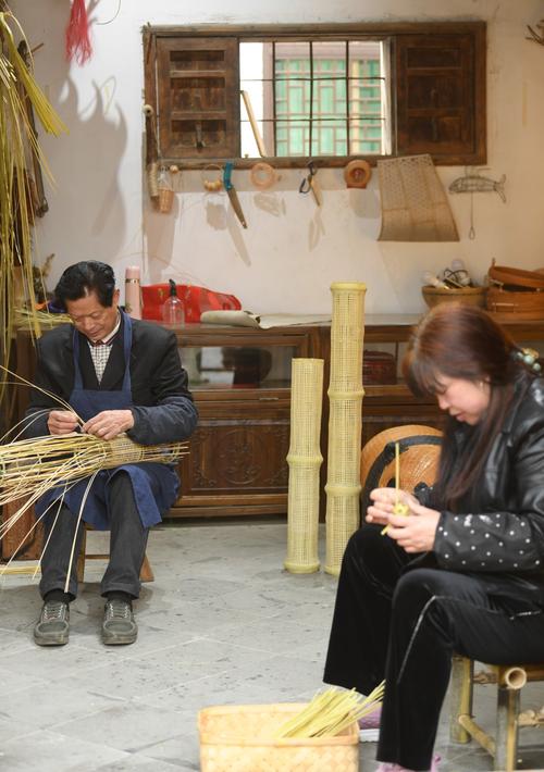 老巷口棕编阿公给蹲在旁边的小孩展示编好的竹螳螂