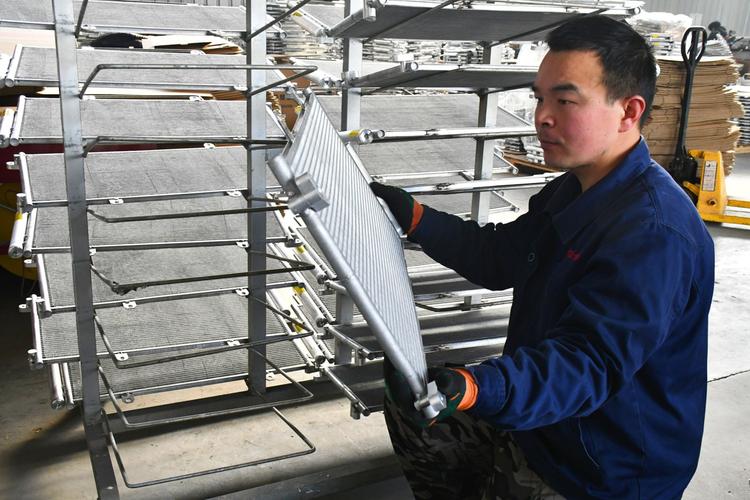 车间工人手持压装完成的工业散热器工件