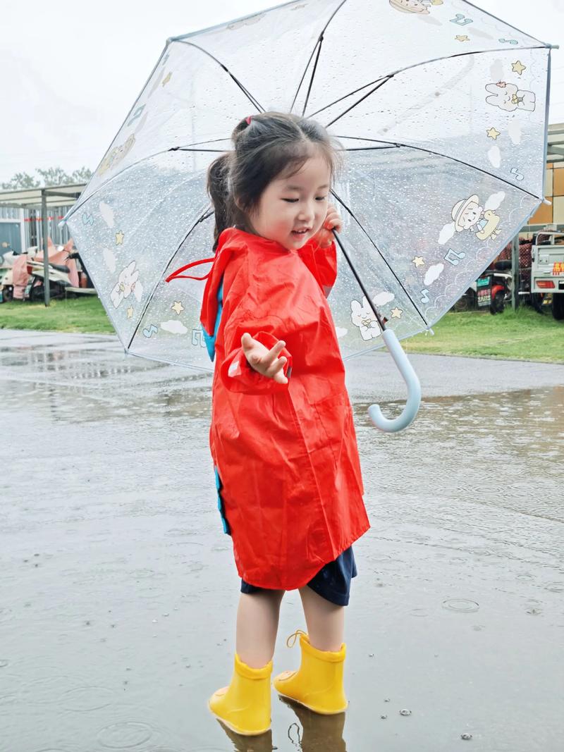 小女孩穿着红色雨鞋踩水坑妈妈在旁微笑守护