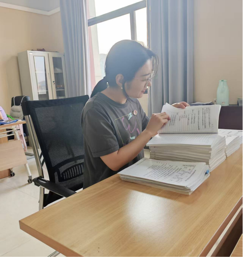 中学校长在教师办公室角落翻看学生作业登记本的特写