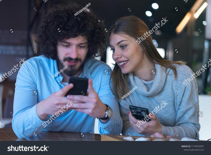 两个朋友在咖啡厅交谈，一个心不在焉地玩手机
