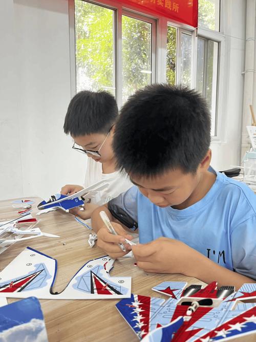 小学手工课上爸爸带孩子粘航模机翼的场景