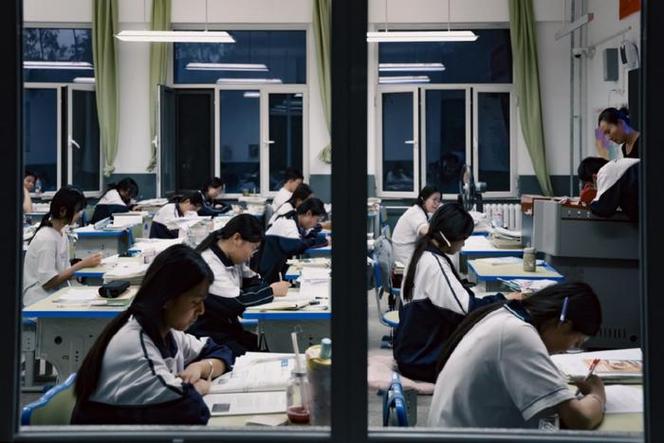 中学晚自修教室靠窗学生攥着皱试卷把脸埋在胳膊上的侧影