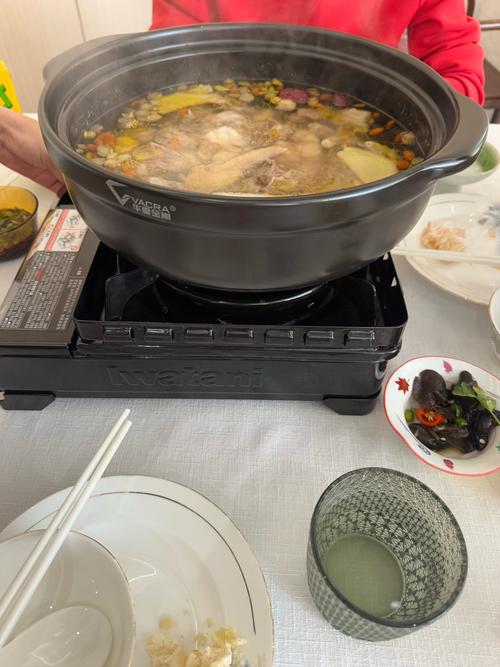 餐桌上放着热汤和打开的电视屏幕