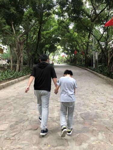 工业工人下班后和孩子在客厅牵手合照