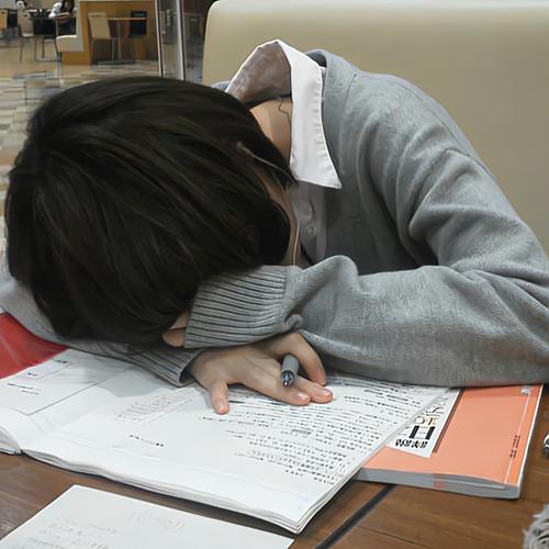 高中生趴在书桌前对着志愿填报手册发呆