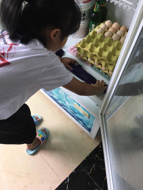 小学三年级女孩蹲在超市冷柜前给鸡蛋按大小分类
