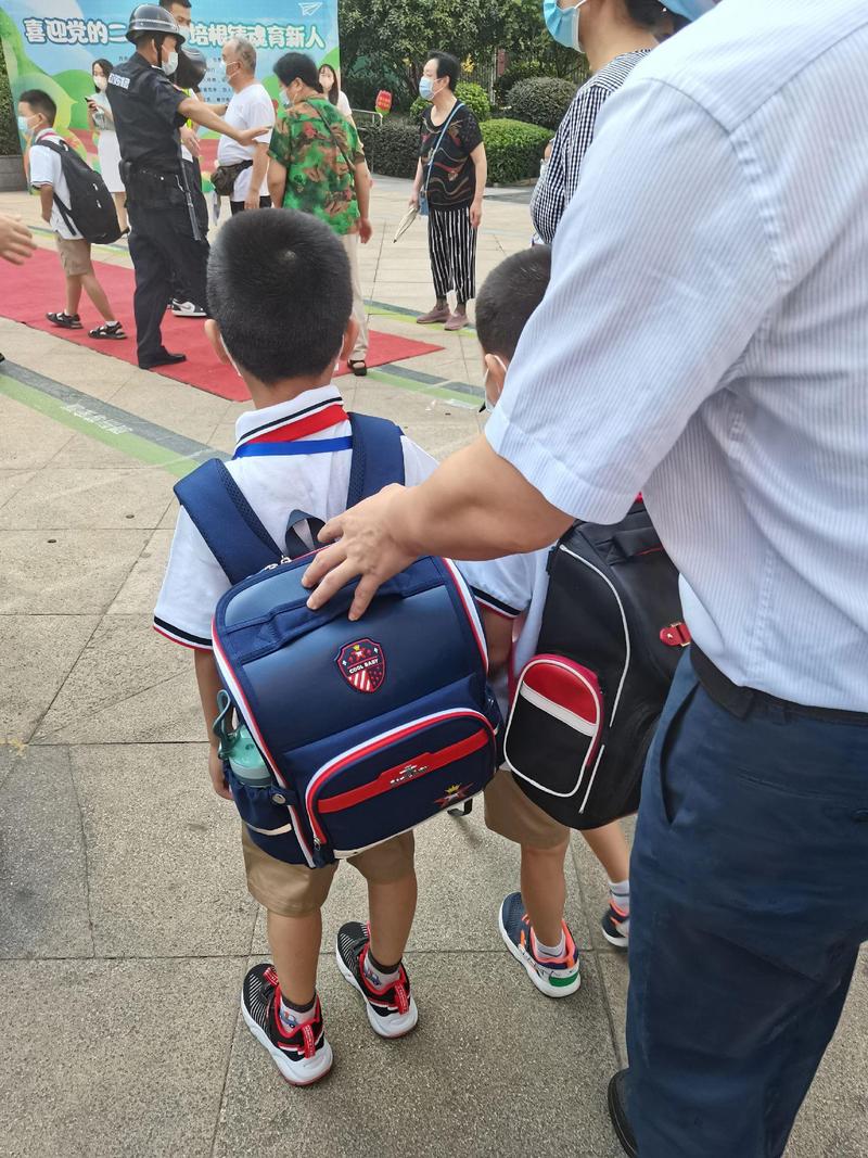 小学一年级学生刚进教室背着滑下来的书包的真实抓拍