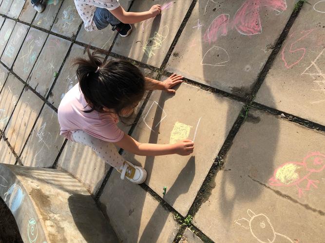 小朋友在小区地砖上用粉笔描自己影子的日常实拍图
