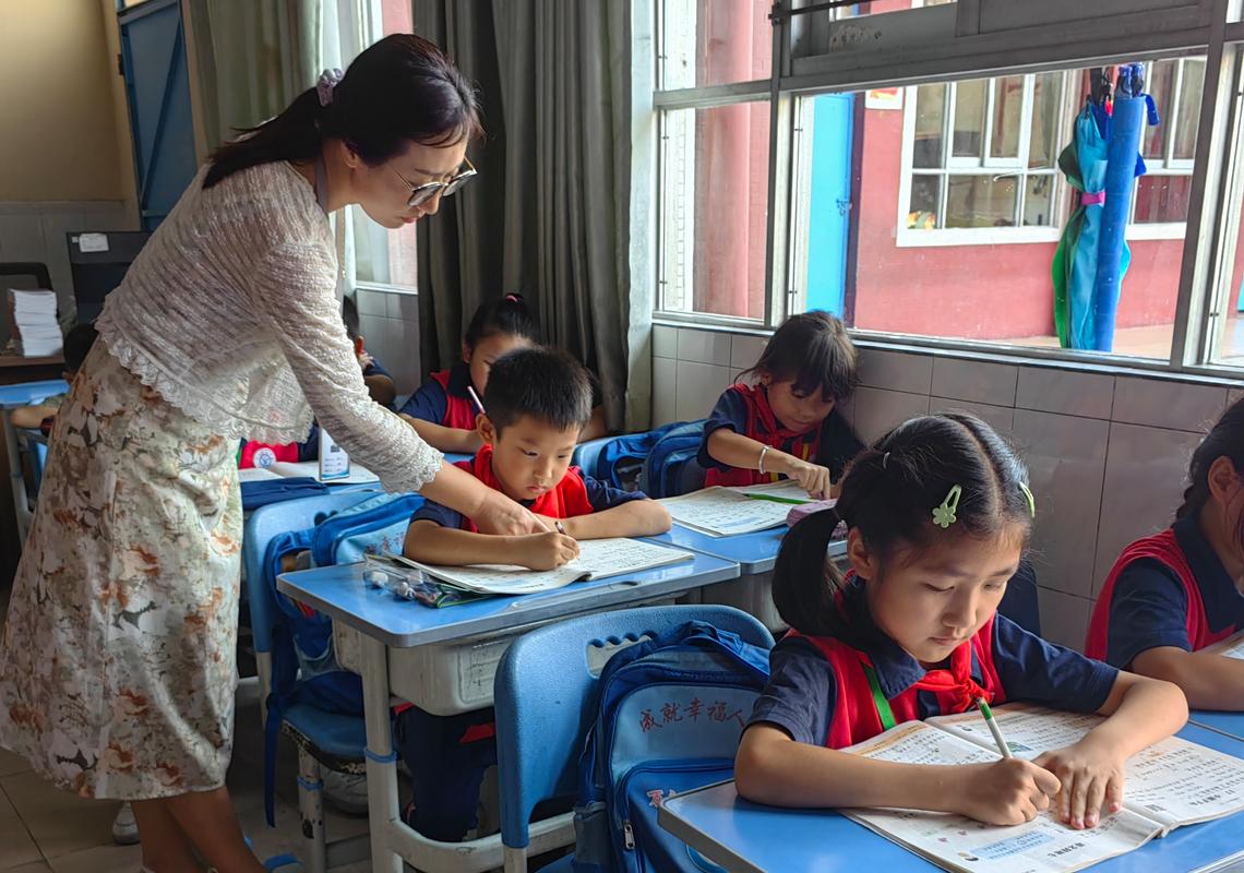 小学课后服务教室老师值守学生伏案写作业的日常场景
