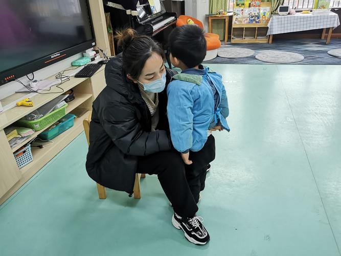 妈妈蹲下来和幼儿园幼儿温和挥手告别场景