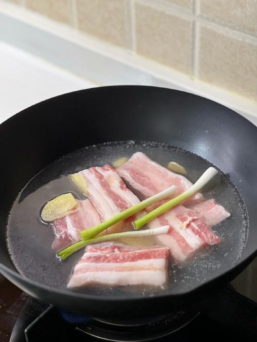 五花肉焯水后温水冲洗的画面，保持肉温