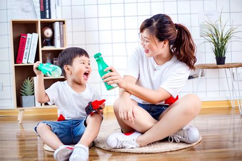 母子并排坐沙发递冰矿泉水场景