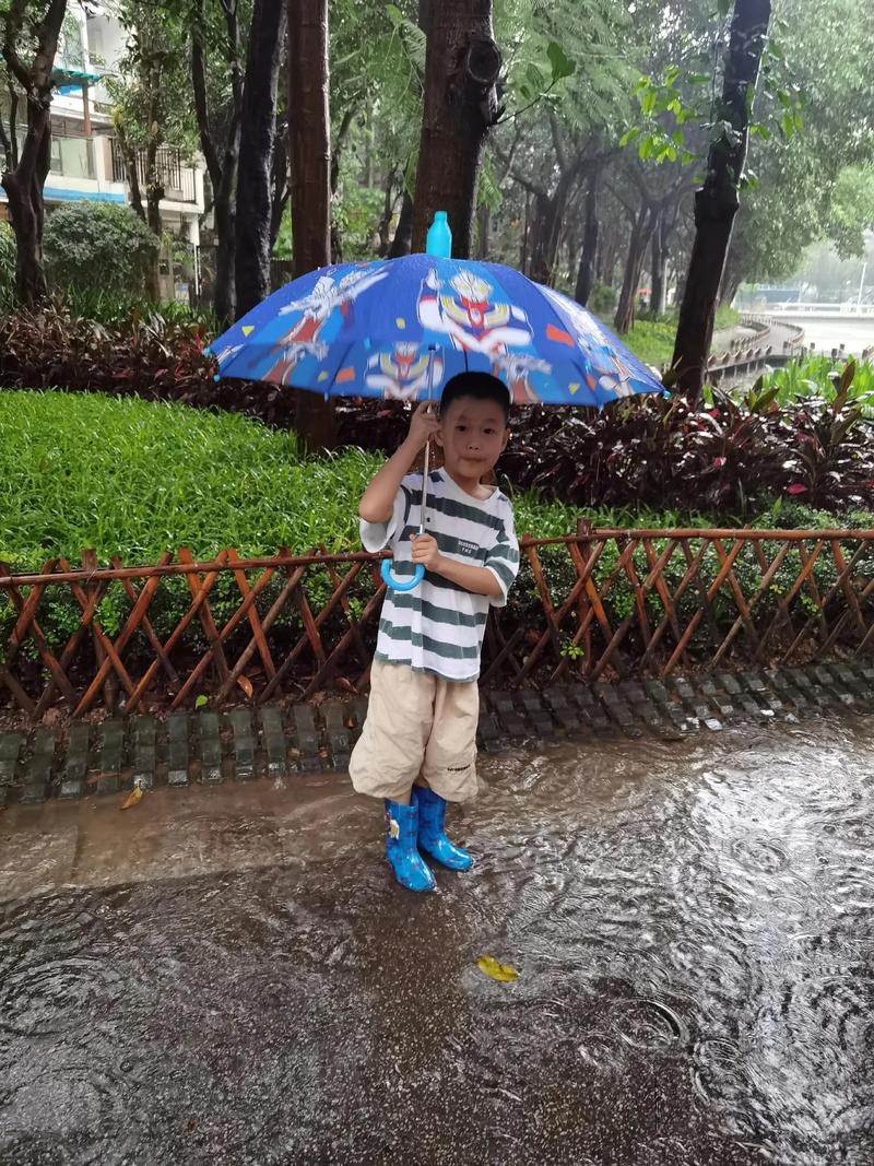 儿童穿雨靴踩水坑玩耍照片