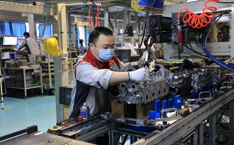 车间工人佩戴工业增强现实头盔组装汽车发动机