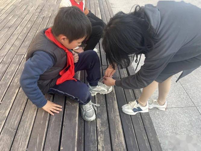 小学走廊老师弯腰给学生系松开的鞋带