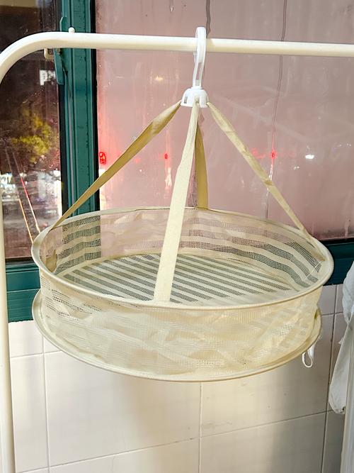 平铺在金属网状晾衣篮上的厚羊毛衫晾晒场景