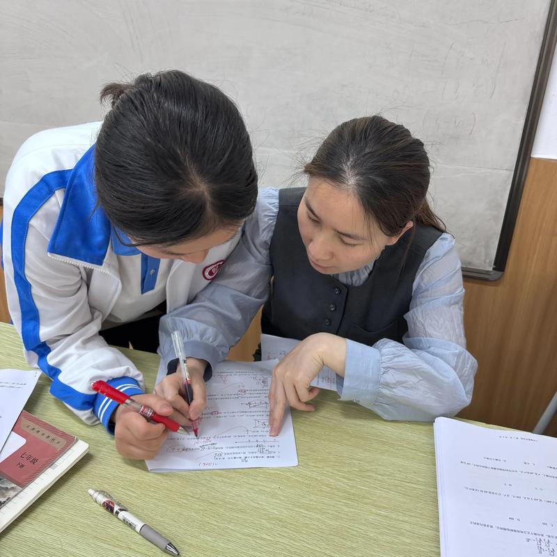 一位男老师正在办公室耐心辅导一个神情沮丧的小学生