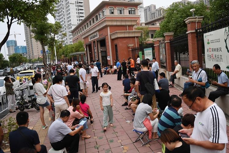 家长在小学门口排队报名划片入学场景